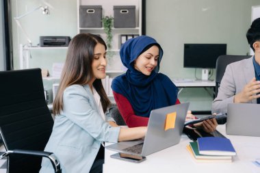 İşadamları yeni bir projede iş birliği yapıyorlar, dizüstü bilgisayar kullanıyorlar ve ofiste beyin fırtınası yapıyorlar.