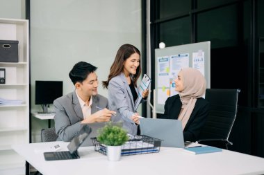 Ofiste beyin fırtınası yaparken dizüstü bilgisayar ve tablet kullanan iş adamları yeni bir projede işbirliği yapıyorlar
