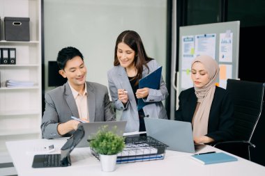 Ofiste beyin fırtınası yaparken dizüstü bilgisayar ve tablet kullanan iş adamları yeni bir projede işbirliği yapıyorlar