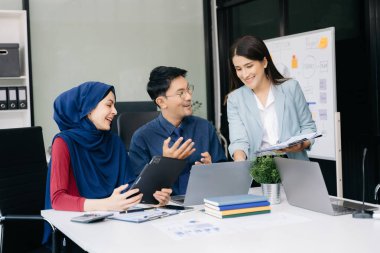 Ofiste beyin fırtınası yaparken dizüstü bilgisayar ve tablet kullanan iş adamları yeni bir projede işbirliği yapıyorlar