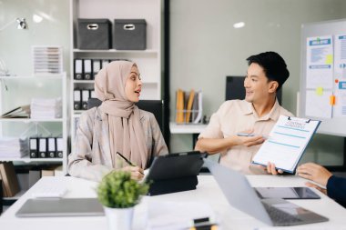 Ofiste beyin fırtınası yaparken dizüstü bilgisayar ve tablet kullanan iş adamları yeni bir projede işbirliği yapıyorlar