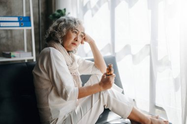 Bunalımda olan bir şişe haplı yaşlı kadın evdeki kanepede oturuyor.