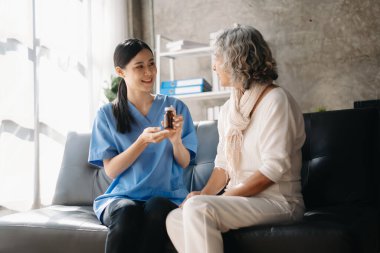 Asyalı bakıcı doktor yaşlı hastaya reçete yazar, klinikteki kanepede oturur. Tıbbi servis kavramı