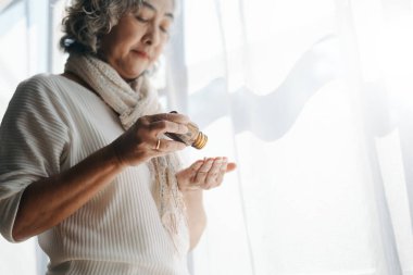 Depresyonda olan bir şişe haplı yaşlı kadın pencerede bekliyor.