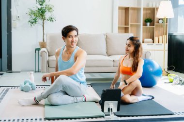 Çift evde enerjik egzersiz yapıyor, dijital tablet kullanıyor, yoga minderleri, spor aletleri ve hareketli aktif yaşam tarzı kullanıyor.