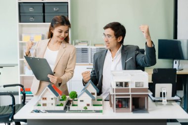 Mimarlar, tasarımcılar veya geliştiricilerin modern ofis toplantısı yenilikçi, sürdürülebilir konut projeleri yaratıyor, ofiste inşa modelleri kullanıyor, el kol hareketi yapıyor