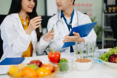 İki genç beslenme uzmanı sağlıklı gıda seçenekleri ve masada taze meyve ve sebzelerle sağlıklı bir yaşam için yemek planlama konusunda danışmanlık yapıyorlar. Dengeli bir yaşam tarzı için diyet tavsiyeleri.