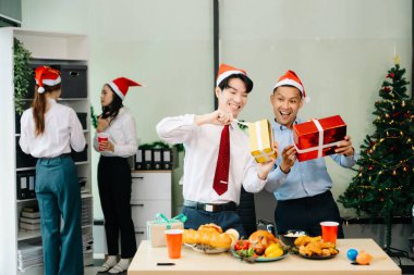 Meslektaşlar Noel 'i neşeli bir ofis partisinde kutluyor, hediyelerini paylaşıyor, ofislerinde gülüyorlar. 