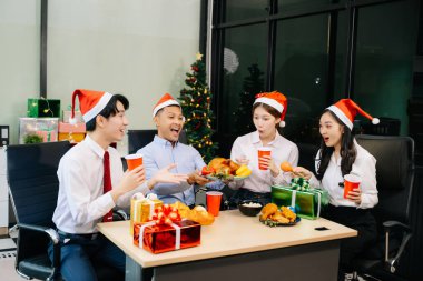 Meslektaşlar Noel 'i neşeli bir ofis partisinde kutluyor, hediyelerini paylaşıyor, ofislerinde gülüyorlar. 