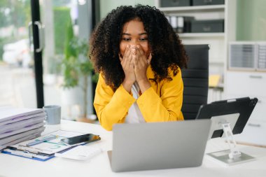 Modern ofiste dizüstü bilgisayarla çalışan Afrikalı Amerikalı iş kadını şaşırdı. 