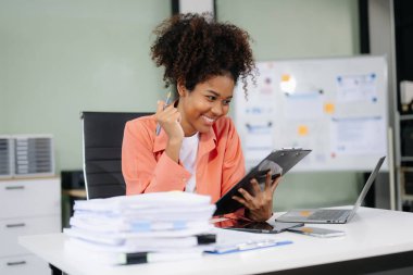 Modern ofiste tablet ve dizüstü bilgisayarla çalışan mutlu Afro-Amerikan iş kadını 