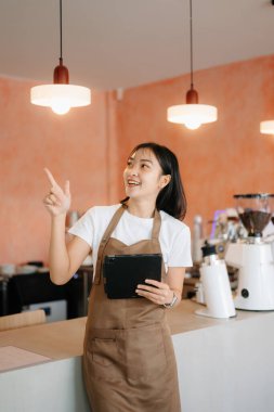 Küçük işletme sahibi başarılı bir kadın kafeteryada çalışırken elinde tablet tutuyor. Kadın kahveci kafe sahibi.. 
