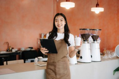 Küçük işletme sahibi başarılı bir kadın kafede çalışırken elinde tablet ve kahve fincanı tutuyordu. Kadın kahveci kafe sahibi.. 