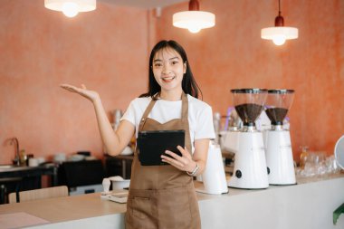 Küçük işletme sahibi başarılı bir kadın kafeteryada çalışırken elinde tablet tutuyor. Kadın kahveci kafe sahibi.. 