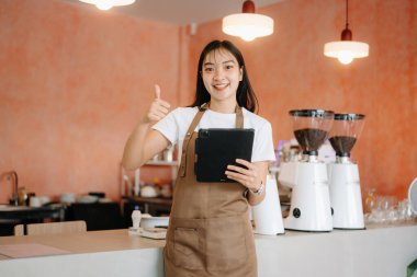 Başlangıçta başarılı bir küçük işletme sahibi olan kadın, kafeteryasında çalışırken elinde tabletle kendini gösteriyor. Kadın kahveci kafe sahibi.. 