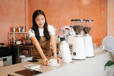 Profesyonel Asyalı bayan barista şık bir kafede kahve yapıyor. Kahve kültürü sergileniyor.