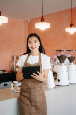 Küçük işletme sahibi başarılı bir kadın kafeteryada çalışırken elinde tablet tutuyor. Kadın kahveci kafe sahibi.. 