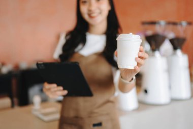 Küçük işletme sahibi başarılı bir kadın kafede çalışırken elinde tablet ve kahve fincanı tutuyordu. Kadın kahveci kafe sahibi.. 