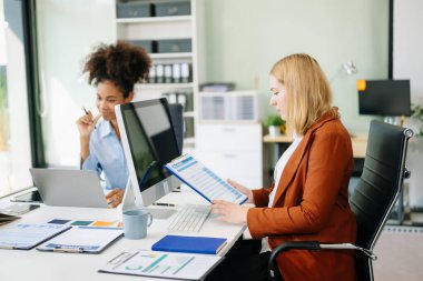 Yeni projeyi bilgisayar ve dizüstü bilgisayar kullanarak tartışan kadın meslektaşlar 