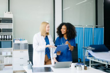 Doktor ve hemşire dizüstü bilgisayar ve dosya kullanıyor, modern hastanede takım çalışması sergiliyorlar. Muhtelif sağlık uzmanları hasta teşhisini tartışıyor 