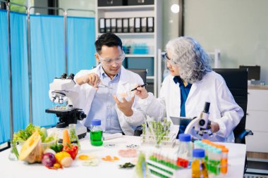 Laboratuvardaki Asyalı bilim adamları mikroskop ve laboratuvar ekipmanları kullanarak gıda araştırmaları yapıyor, gıda bilimi ve biyoteknoloji alanında yenilikler sergiliyorlar.