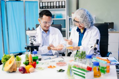 Laboratuvardaki Asyalı bilim adamları mikroskop ve laboratuvar ekipmanları kullanarak gıda araştırmaları yapıyor, gıda bilimi ve biyoteknoloji alanında yenilikler sergiliyorlar.