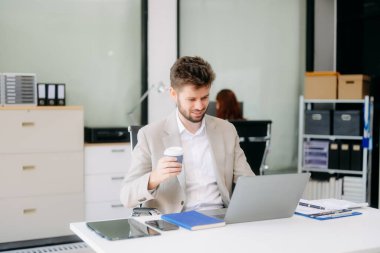 Çalışan not defteri, tablet ve dizüstü bilgisayarla çalışan genç işadamı akıllı telefon, tablet ve dizüstü bilgisayardaki video arama vergisi, rapor