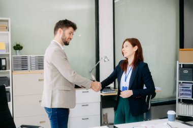 Ofisteki bir toplantıda iki iş adamı el sıkışıyor.