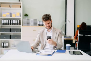 Çalışan not defteri, tablet ve dizüstü bilgisayarla çalışan genç işadamı akıllı telefon, tablet ve dizüstü bilgisayardaki video arama vergisi, rapor