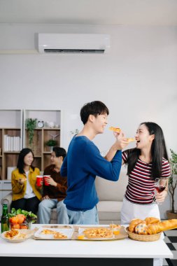 Bir grup Asyalı genç arkadaş evde akşam partisinin tadını çıkarıyorlar. Çekici genç erkek ve kadınlar eğleniyor, yemek yiyor ve içkiden zevk alıyor, modern evde kutlama yapıyorlar.