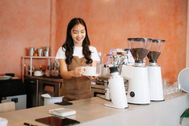 Kahve dükkanında kahve yapan Asyalı barista ve şık bir kafede kahve kültürü sergiliyor.