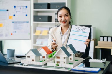 Ofiste sözleşmeli çalışan genç bir emlakçı ve yanında da küçük ev modelleri.. 