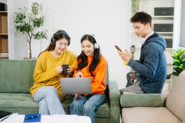 Bir grup genç Asyalı üniversite öğrencisi, dizüstü bilgisayar ve tablet kullanarak onun proje ödevi üzerinde çalışıyorlar. Birlikte, konuşmanın ve evde atıştırmanın tadını çıkarın.