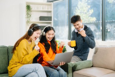 Gündelik kıyafetleri ve kulaklıkları olan genç yetişkinlerden oluşan canlı bir grup dizüstü bilgisayarlar, el hareketleriyle hareket eden eller, takım çalışmasının, yaratıcılığın ve rahat bir ortamda öğrenmenin tadını çıkarıyor. 