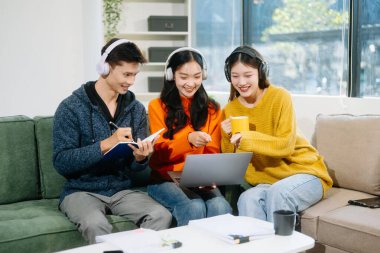 Gündelik kıyafetleri ve kulaklıkları olan genç yetişkinlerden oluşan canlı bir grup dizüstü bilgisayar kullanıyor, takım çalışmasından, yaratıcılıktan ve rahat bir ortamda öğrenmekten keyif alıyor. 