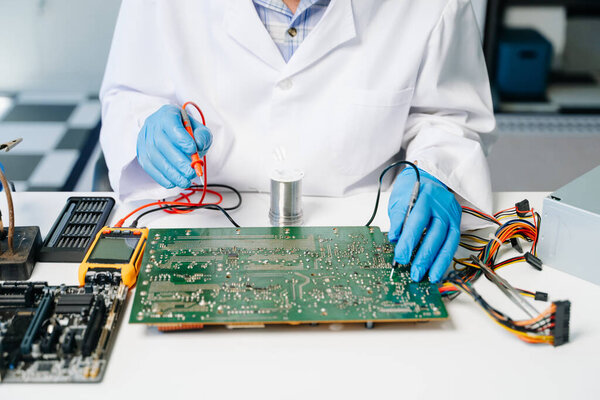 Техник, ремонтирующий материнскую плату в мастерской 
