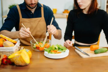 Evde yemek yapan bir çift. Genç çift ekmek ve taze sebzelerle birlikte yemek pişiriyor, sıcacık mutfakta sağlıklı besleniyorlar. Sağlıklı yaşam tarzı için mükemmel. 