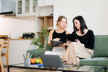 İki genç kadın yeşil kanepede rahat bir odada tablet kullanıyor. Canlı takım çalışmasını, yaratıcılığı ve genç yetişkinlerle öğrenmeyi keşfedin.. 