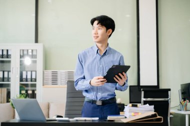 Ofiste dijital tablet ve dizüstü bilgisayarla çalışan genç bir iş adamı.