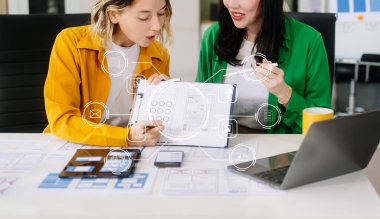 Modern ofiste müşteri özeti ve renk kodu ile mobil uygulama arayüzü kablo tasarımı hakkında fikir alışverişi yapan UX geliştiricisi ve ui tasarımcısı üzerindeki web simgeleri.