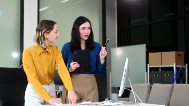 Ofiste birlikte çalışan iki iş kadını yeni bir proje yürütüyor ve dijital tablet bilgisayar kullanıyorlar. 