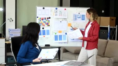 Ofiste birlikte çalışan iki iş kadını, yönetim kurulunu kullanarak yeni bir proje yürütüyorlar.