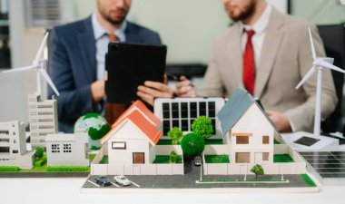 Uzmanlar ev modelleri, rüzgar türbinleri ve güneş panelleri ile yenilenebilir enerji çözümleri üzerinde işbirliği yaparak, dijital tablet bilgisayar kullanarak yeşil tasarım ve yenilikleri vurguluyorlar. 