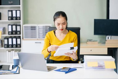Modern ofiste tablet ve dizüstü bilgisayarla çalışmaktan yorgun ve çok düşünen Asyalı bir kadın.