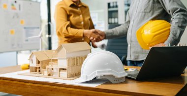 İnşaat ekibi, inşaat projeleriyle ilgili danışmanlık yapmak için ofis merkezindeki sarı miğferin arkasında yeni proje planını başlatın..