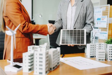 İş adamları, konut projesinden kalma bina modeliyle el sıkışıyorlar. Yeşil iş şirketi ve Güneş Enerjisi Çevre Kenti Kavramı