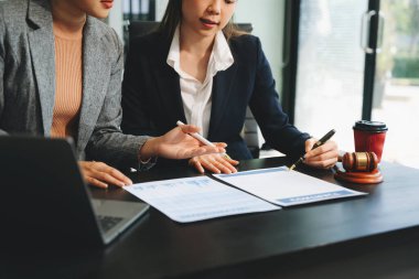 İş adamları ve avukatlar masada oturup dizüstü bilgisayar kullanarak sözleşme belgelerini tartışıyorlar. Hukuk kavramları, tavsiyeler, hukuk hizmetleri