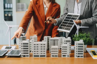 Neare 'de oturan çeşitli etnik çeşitliliğe sahip iş adamlarından oluşan bir ekip konut projesinin modeline bakıyor. Yeşil iş şirketi ve Güneş Enerjisi Çevre Kenti Kavramı
