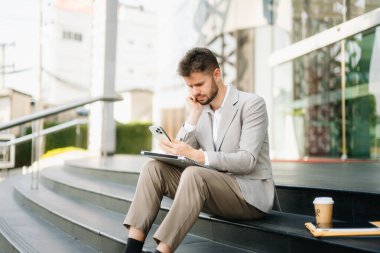 Modern iş adamı açık havada, tablet kullanıyor. İş, teknoloji ve yenilik temaları için idealdir. Kurumsal, profesyonel ve şehir yaşam tarzı kavramı
