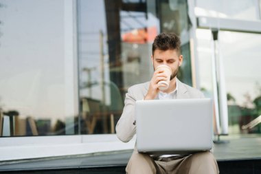 Yakışıklı, traşsız iş adamı. Şehir caddesinde dizüstü bilgisayarla, tabletle ve akıllı telefonla dolaşıyor.